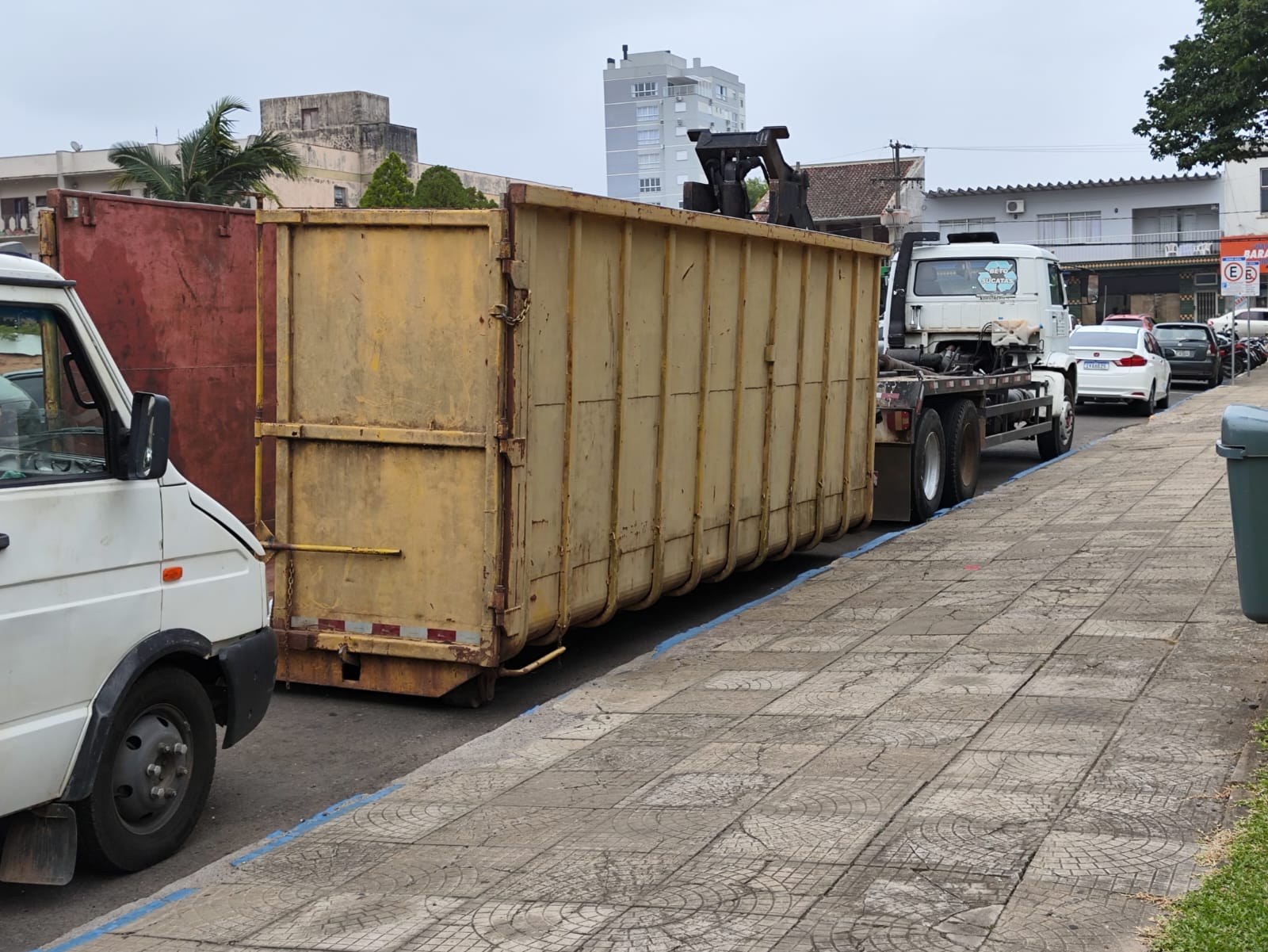 Caminhão coletor com contêiner estacionado em rua, durante coleta de materiais recicláveis